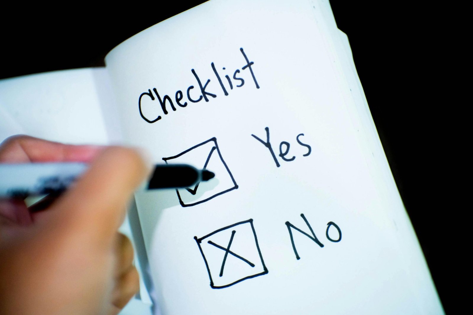 newborn essentials checklist: Close-up of a checklist with a checked box labeled 'Yes' and an unchecked box labeled 'No', with a hand holding a black marker.