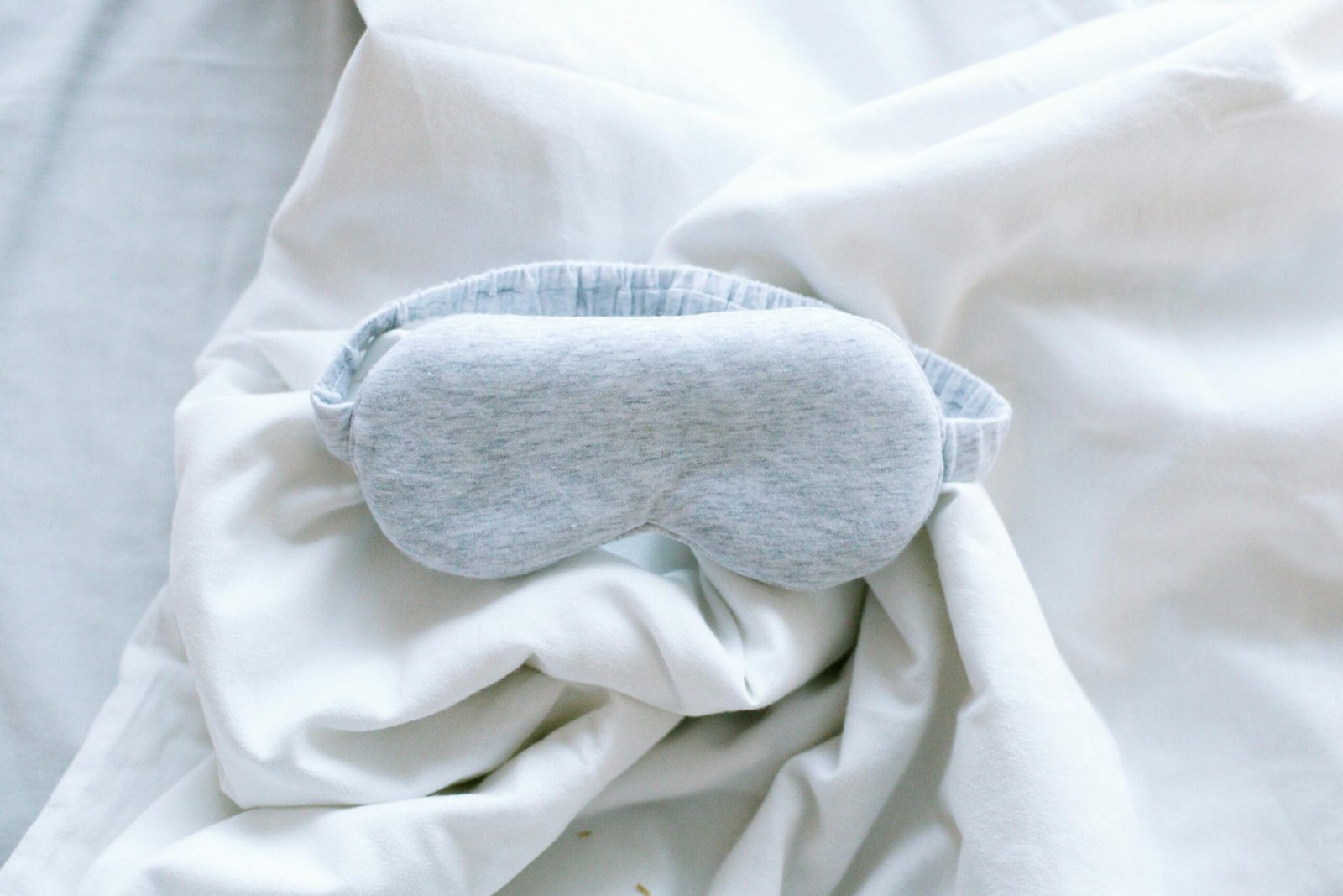 The Ultimate New Baby Hospital Bag Checklist 3 A soft grey sleep mask resting on rumpled white bed sheets.