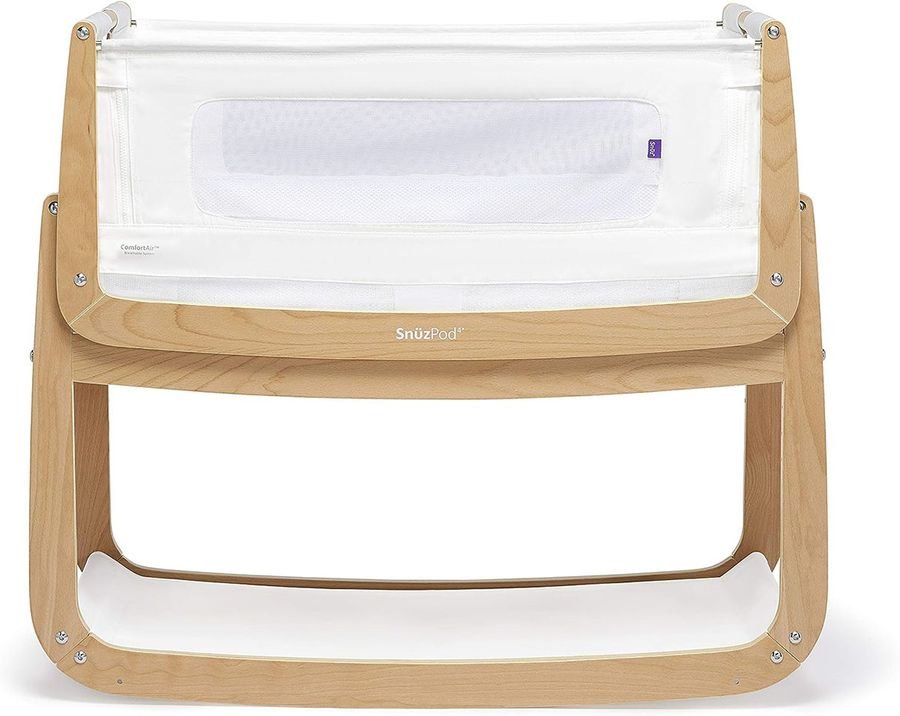 A wooden baby crib with a white fabric and mesh side panel, designed in a modern and compact style.